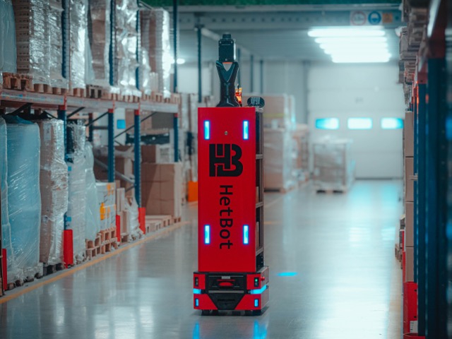 Autonomiczny robot mobilny HetBot poruszający się samodzielnie w magazynie między regałami z towarem.